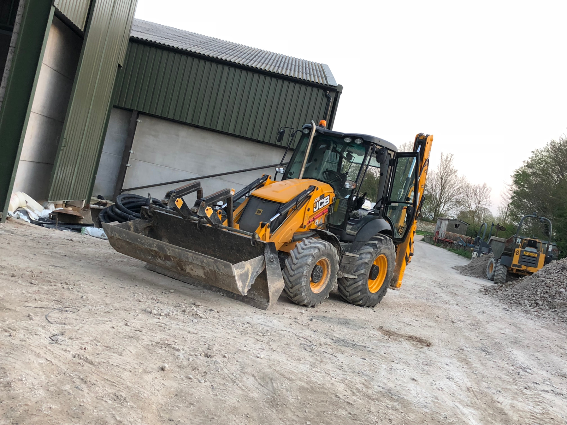 Backhoe loader carrying out groundworks on a prepared construction site